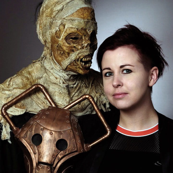 Millennium FX Director, Kate Walshe standing next to a special effect mummy and a Cyberman mask